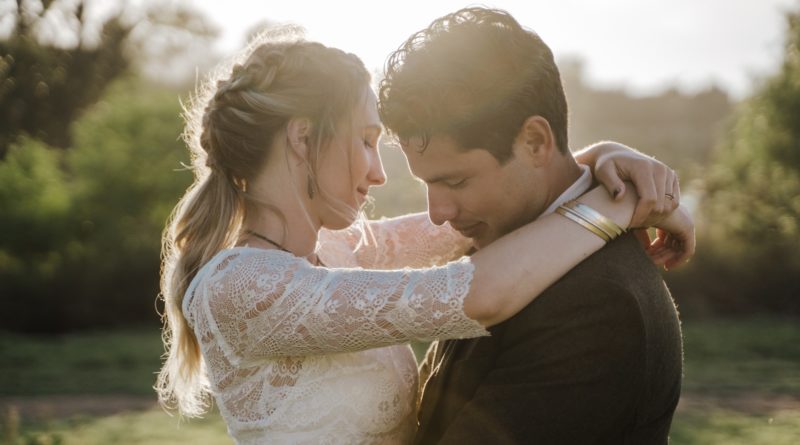 man in black suit kissing woman in white lace long sleeve dress during daytime