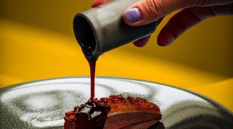 person pouring chocolate on chocolate cake