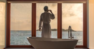 man standing in bathroom with bathtub next to body of water