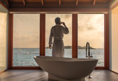 man standing in bathroom with bathtub next to body of water