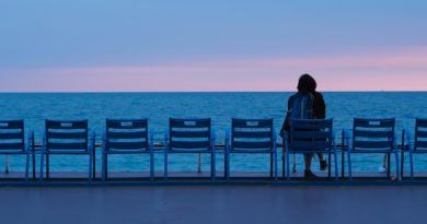 person sitting on blue wooden bench on beach during daytime