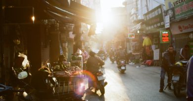 man holding motorcycle on road between buildings