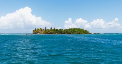 green island surrounded by body of water under blue sky during daytime