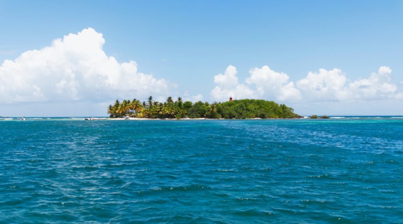 green island surrounded by body of water under blue sky during daytime