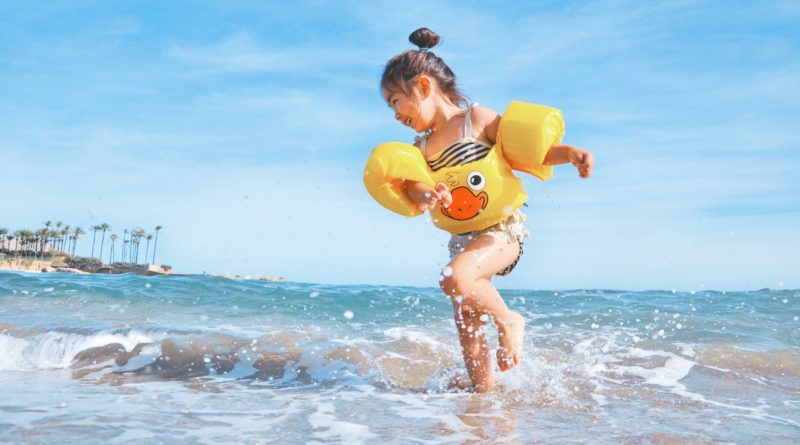 girl playing beside body of water during daytime