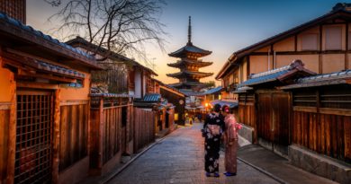 two women in purple and pink kimono standing on street