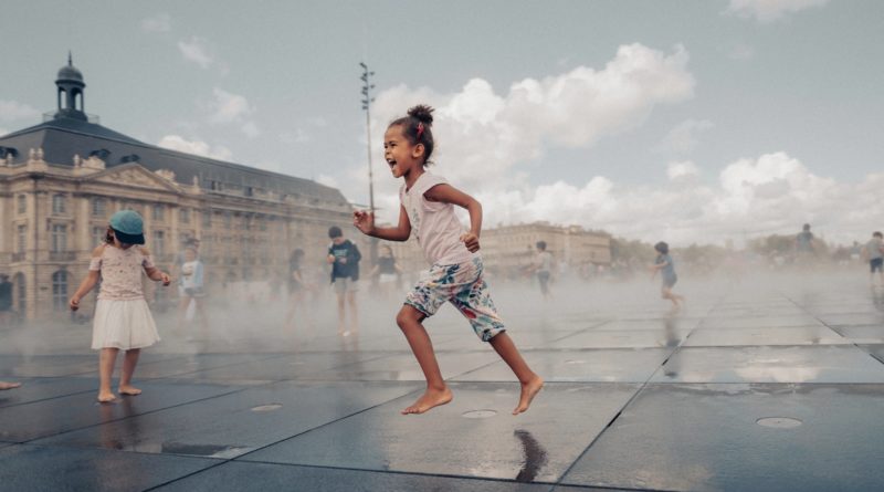 woman in white and red floral tank top and blue denim shorts running on black concrete