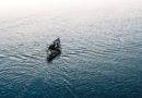 person riding on black kayak on body of water during daytime