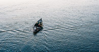 person riding on black kayak on body of water during daytime