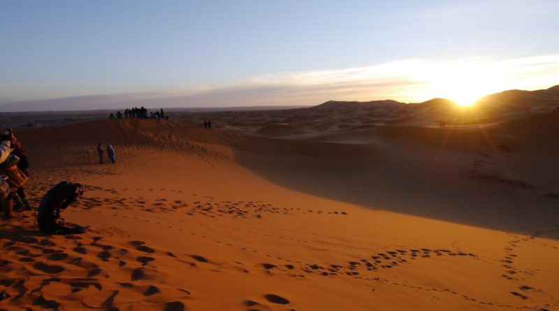 people walking on sand during sunset