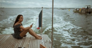 woman sitting on wooden deck above body of water