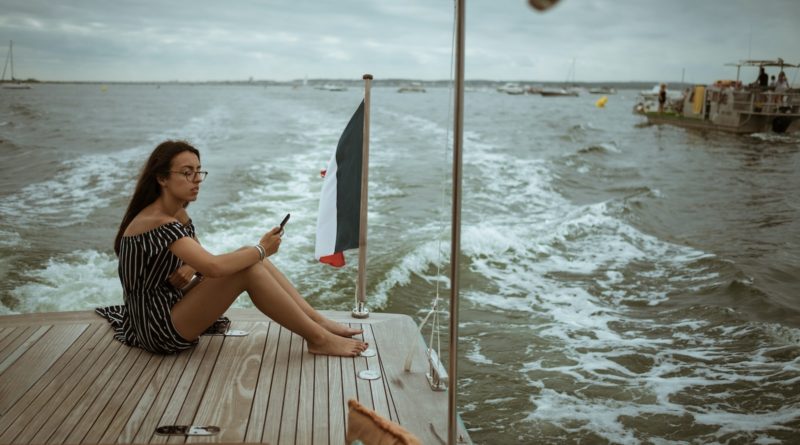 woman sitting on wooden deck above body of water